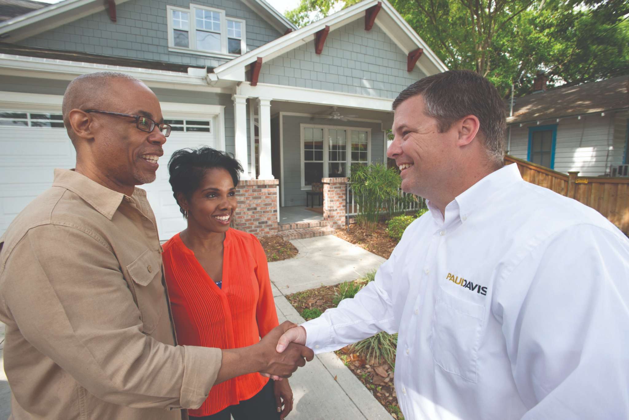 Paul Davis Restoration of Portland / Vancouver representative shaking hands with homeowners outside their house, demonstrating trusted restoration service.